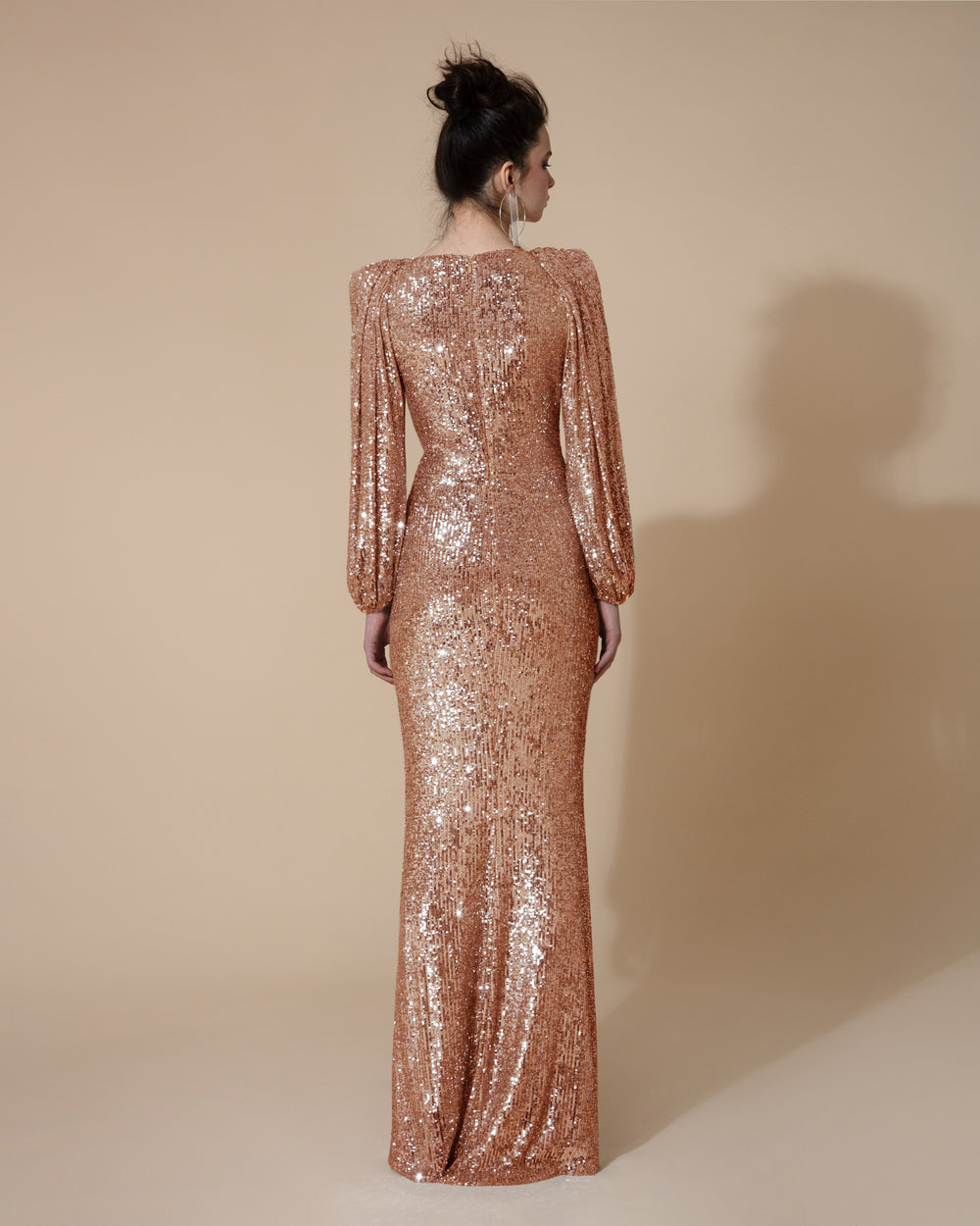 The back of a long evening dress in full copper sequins fabric, with long bishop sleeves.