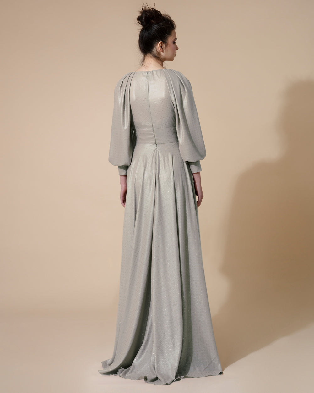 The back of a long silver evening dress with long bishop sleeves.