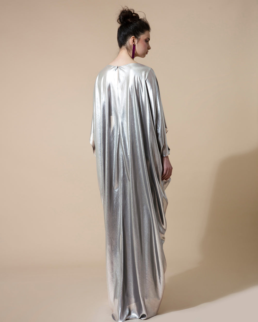 A Cape-like long draped evening dress in metallic silver fabric.