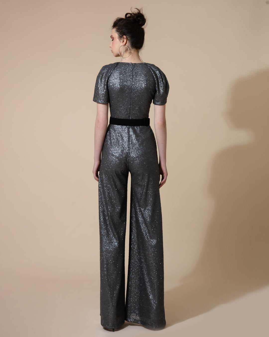 The back of a dark grey jumpsuit with short puffy sleeves and wide legs paired with a black belt.