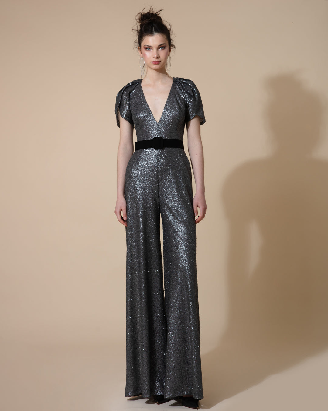 A dark grey jumpsuit with short puffy sleeves, deep V neck and wide legs paired with a black belt.