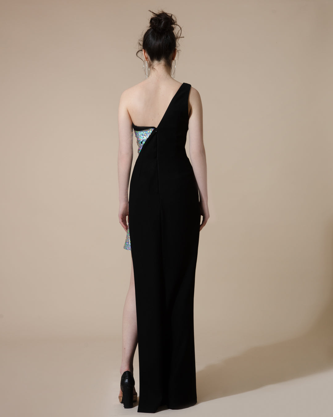 The back of a bi-fabric, black crepe and silver sequined, fitted evening dress with an asymmetrical length.