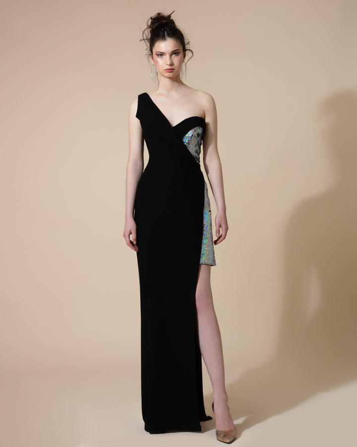 A bi-fabric, black crepe and silver sequined, fitted evening dress with a princess cut on one side and a lapel on the other with an asymmetrical length.