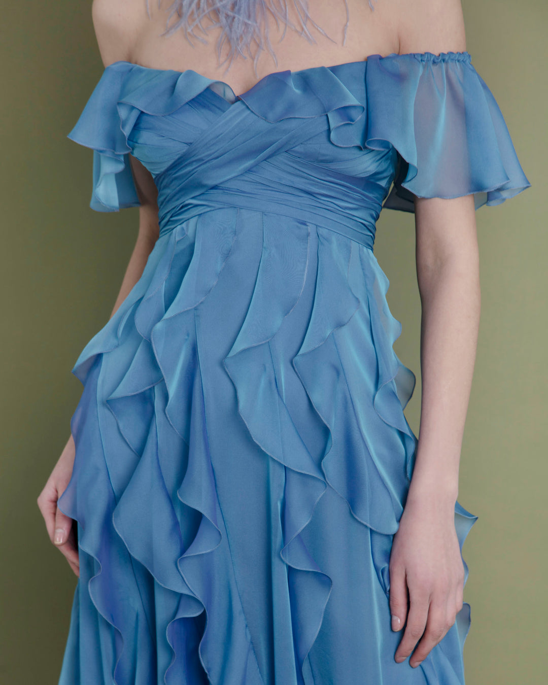 A close-up of a flared cut off-shoulders blue evening dress featuring fully ruffled details.