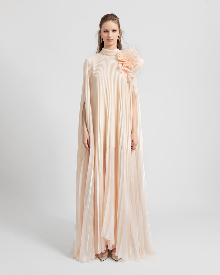 A fully pleated lame organza flared beige dress with an embellished draped flower on the shoulder.