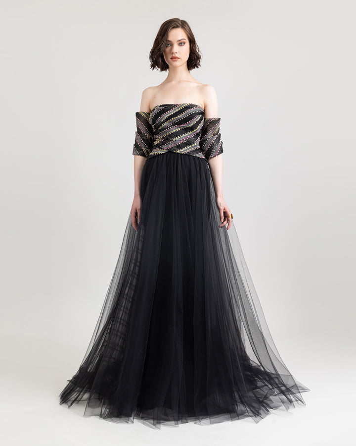 An off-the-shoulder evening dress with draping  on the bust and a flared black tulle skirt.