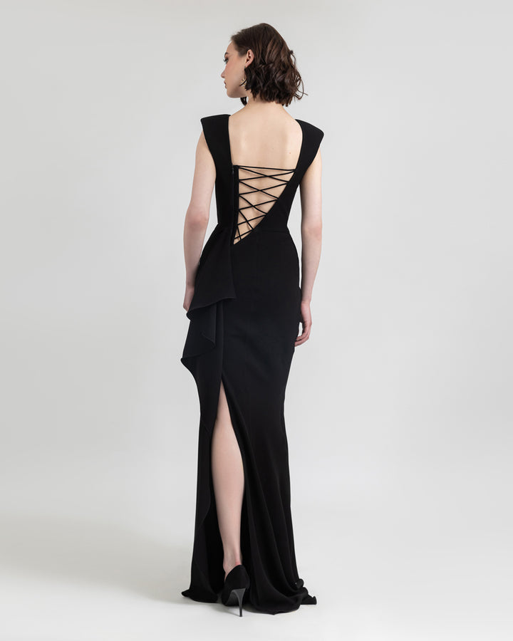 A slim cut black evening dress with a lace-up backless design and ruffles details on a side slit.