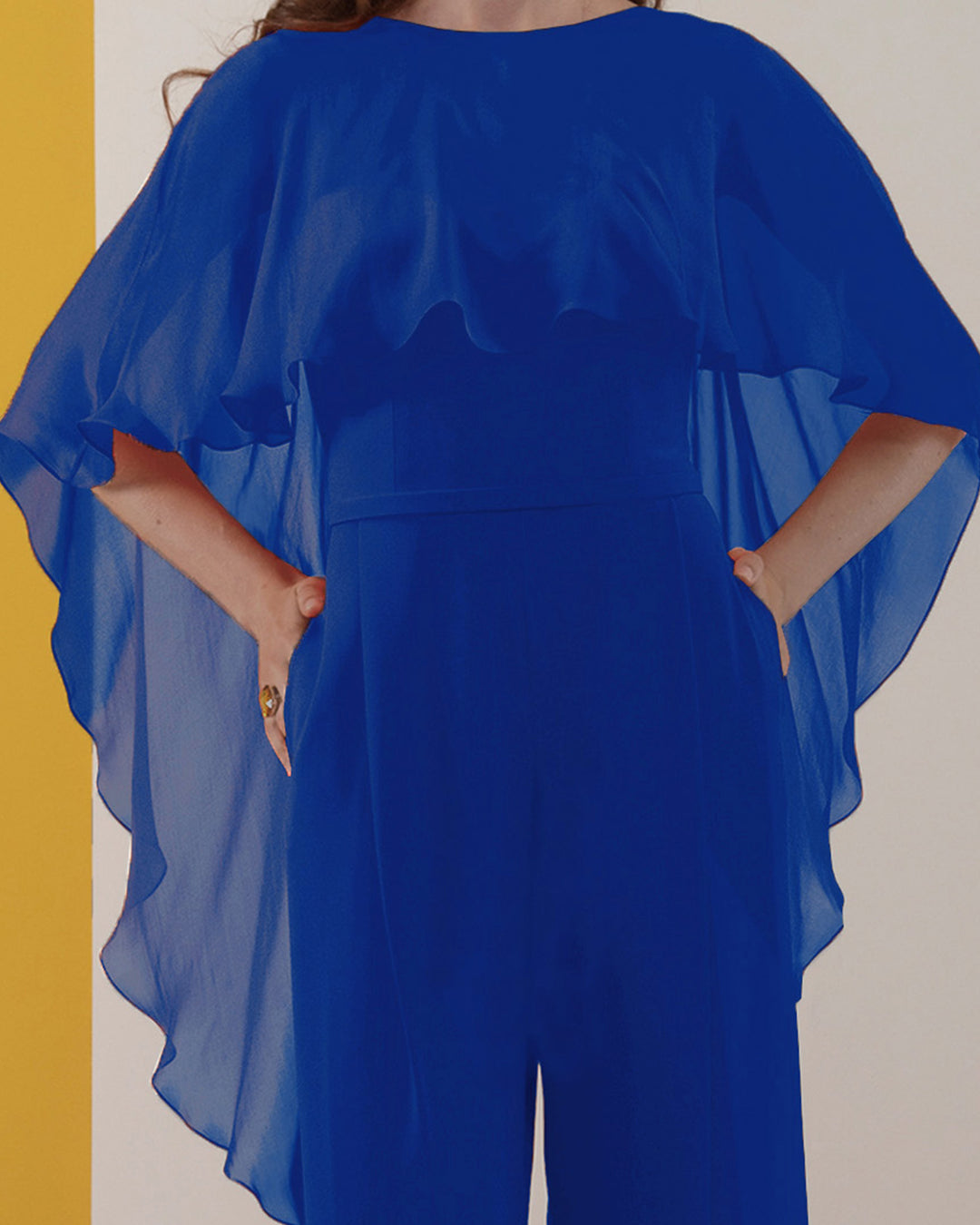 A close-up of a blue jumpsuit with backless design and ruffled flowy chiffon cape-like neckline.