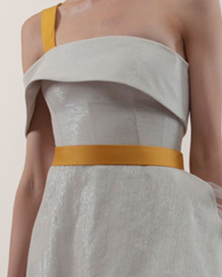 A close-up of an off-shoulders cut dress in a laminated mikado fabric and a detachable yellow crepe belt and strap.