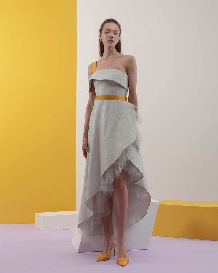 An off-shoulders cut short dress with ruffled tulle underlaying the asymmetrical hemline details in a laminated mikado fabric and a detachable yellow crepe belt and strap.