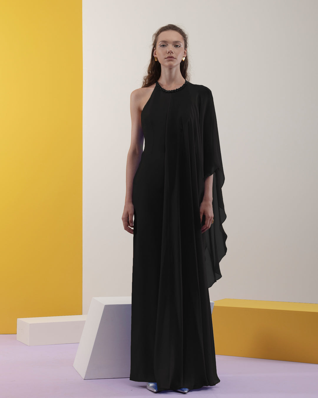 A rounded neckline, slim cut crepe black dress with one sided draped flowy chiffon fabric.