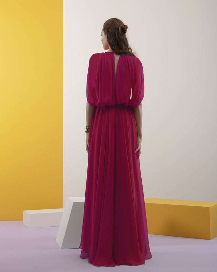 The back of a long fuchsia evening dress in chiffon fabric, with cape-like sleeves and a slightly open back.