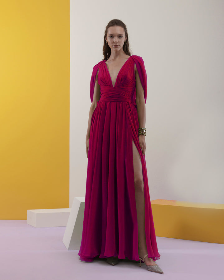 A deep V-neckline, chiffon fabric long evening dress with cape-like sleeves, draped details on the waist, and an open slit on the side.