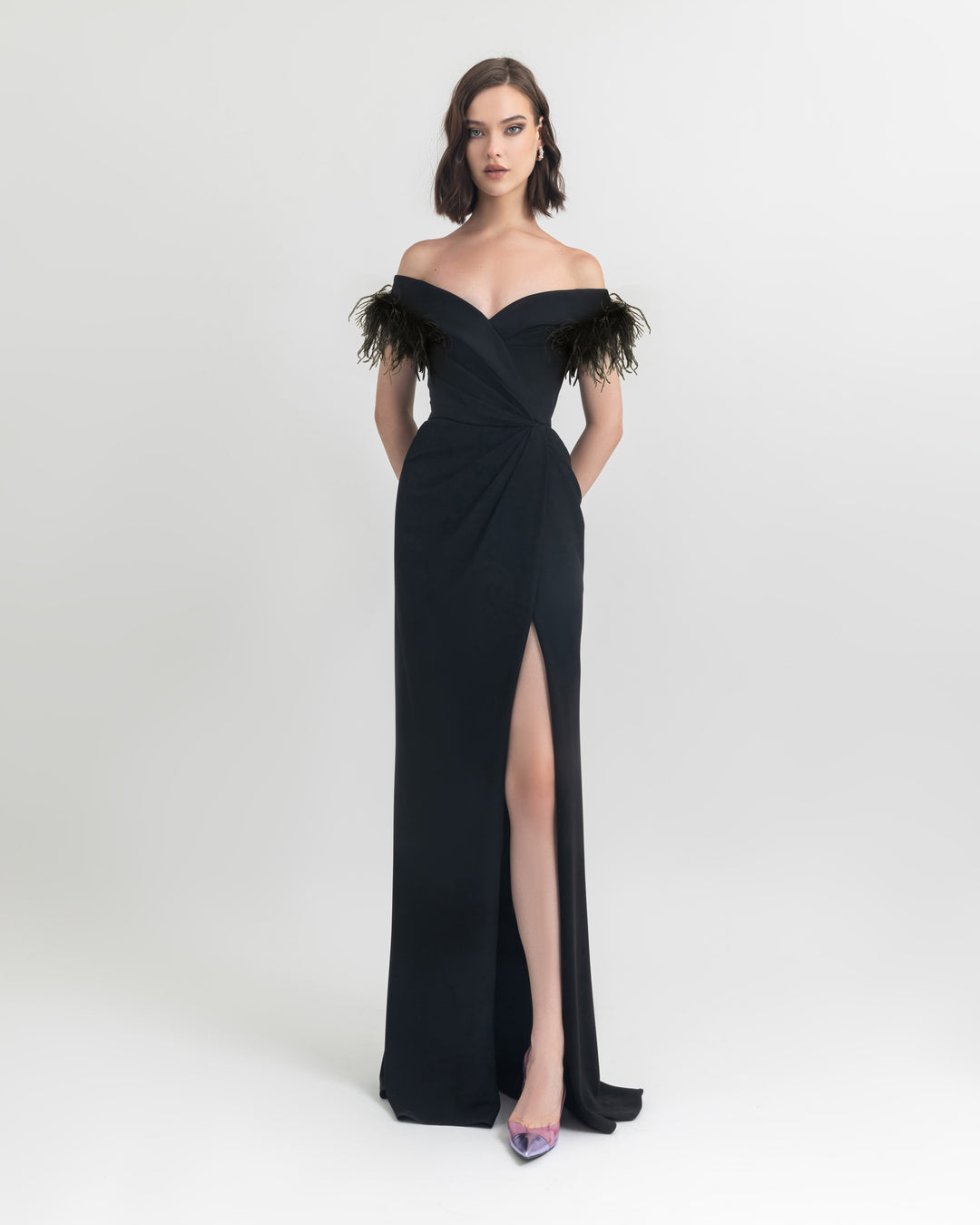 A feathers off shoulder slim cut crepe long black dress with draping details on the waist and an open slit on the side.