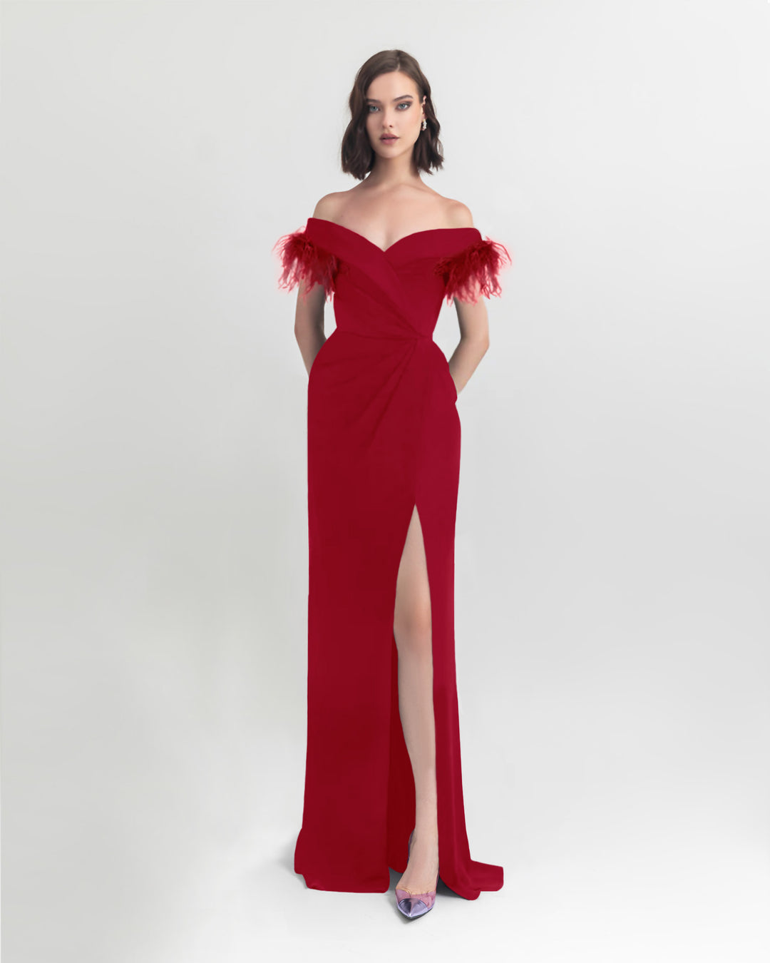 A feathers off shoulder slim cut long red dress with draping details on the waist and an open slit on the side.