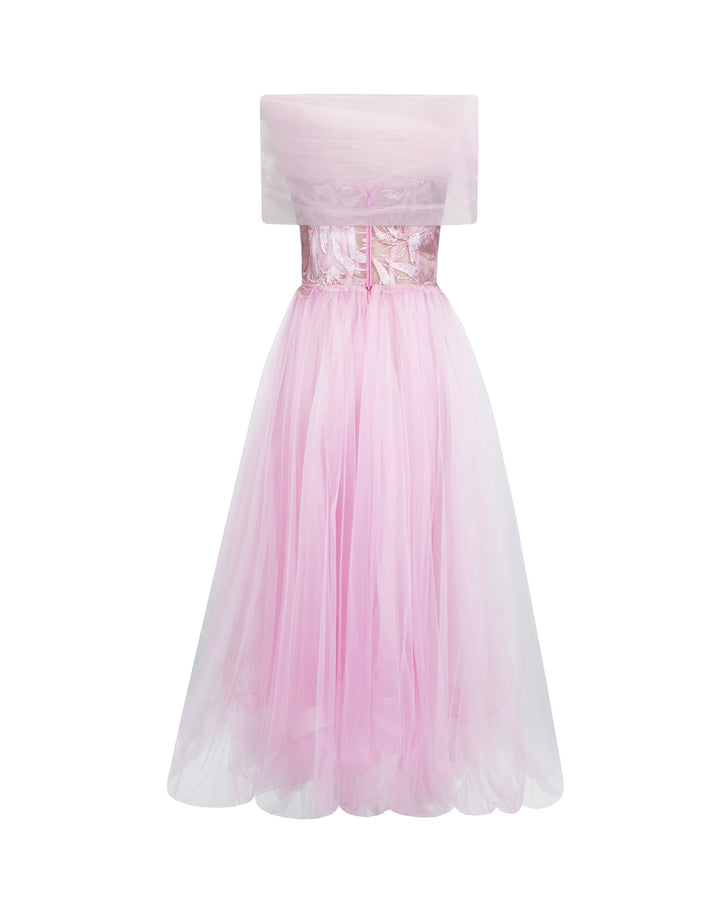 The back of an off-shoulder cut tulle dress in pink with an embroidered corset and an asymmetrical ruffled skirt.