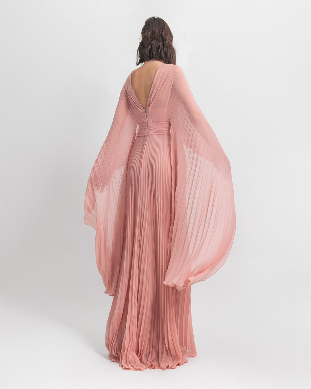 A V-shape open back  fully pleated flared chiffon dress in pink with draping details.