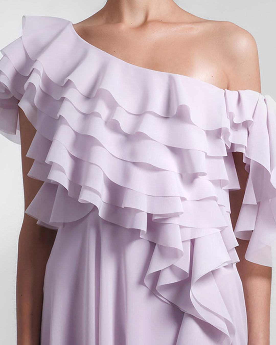 A close-up of a one-shoulder chiffon evening dress with ruffled bodice details.