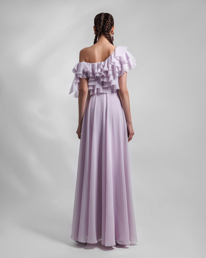 The back of a one-shoulder lilac evening dress in chiffon fabric with ruffled bodice details and an open slit on the side.