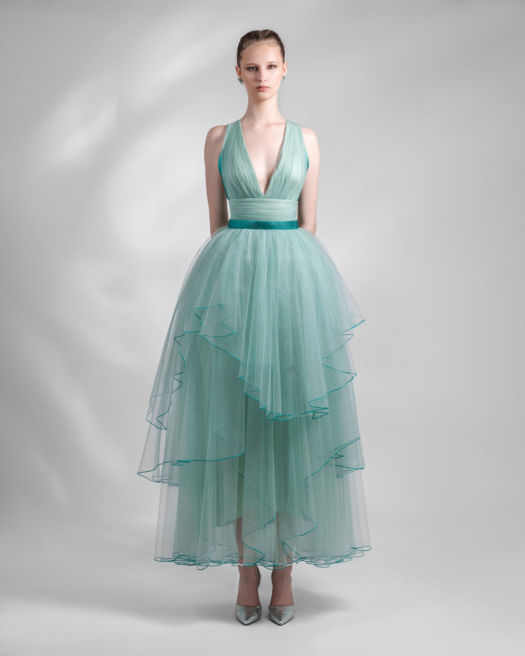 A deep V-neckline mint evening dress with a draped bodice, a beaded belt, and an asymmetrical tulle skirt layering.