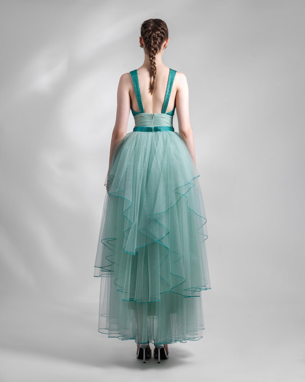 The back of a mint tulle evening dress with a draped waist, beaded belt and straps, and an asymmetrical tulle skirt layering.