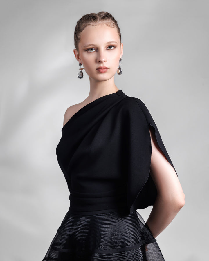 A close p of a black evening wear set featuring an asymmetrical draped crepe top with slits on the sleeves, matched with a cage-like skirt.