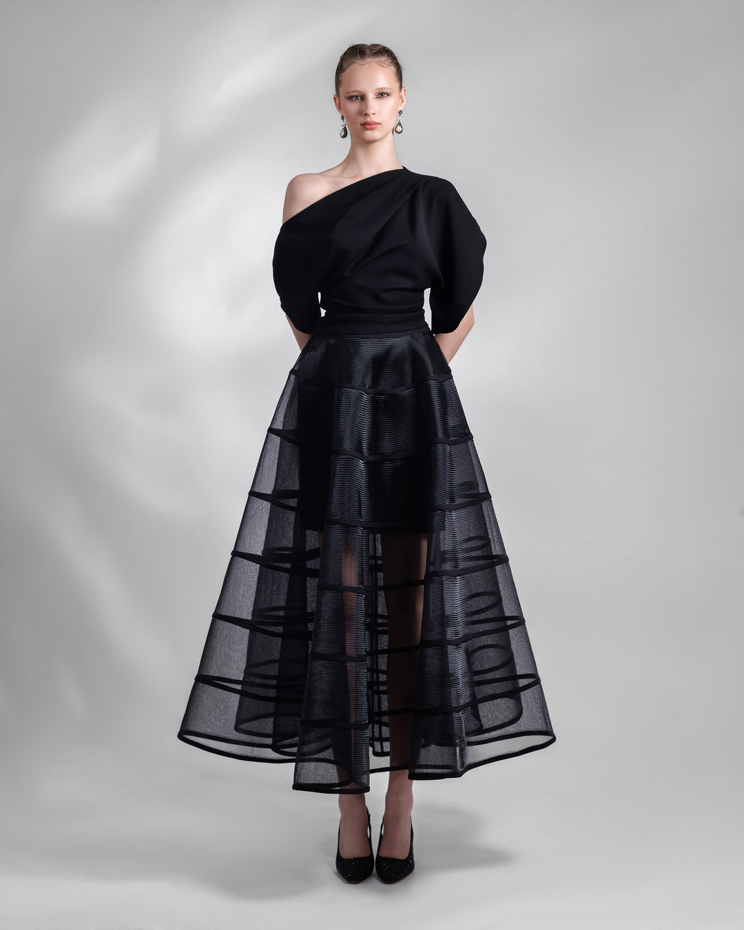 An evening set featuring an asymmetrical neckline black top with a cage-like long black skirt.