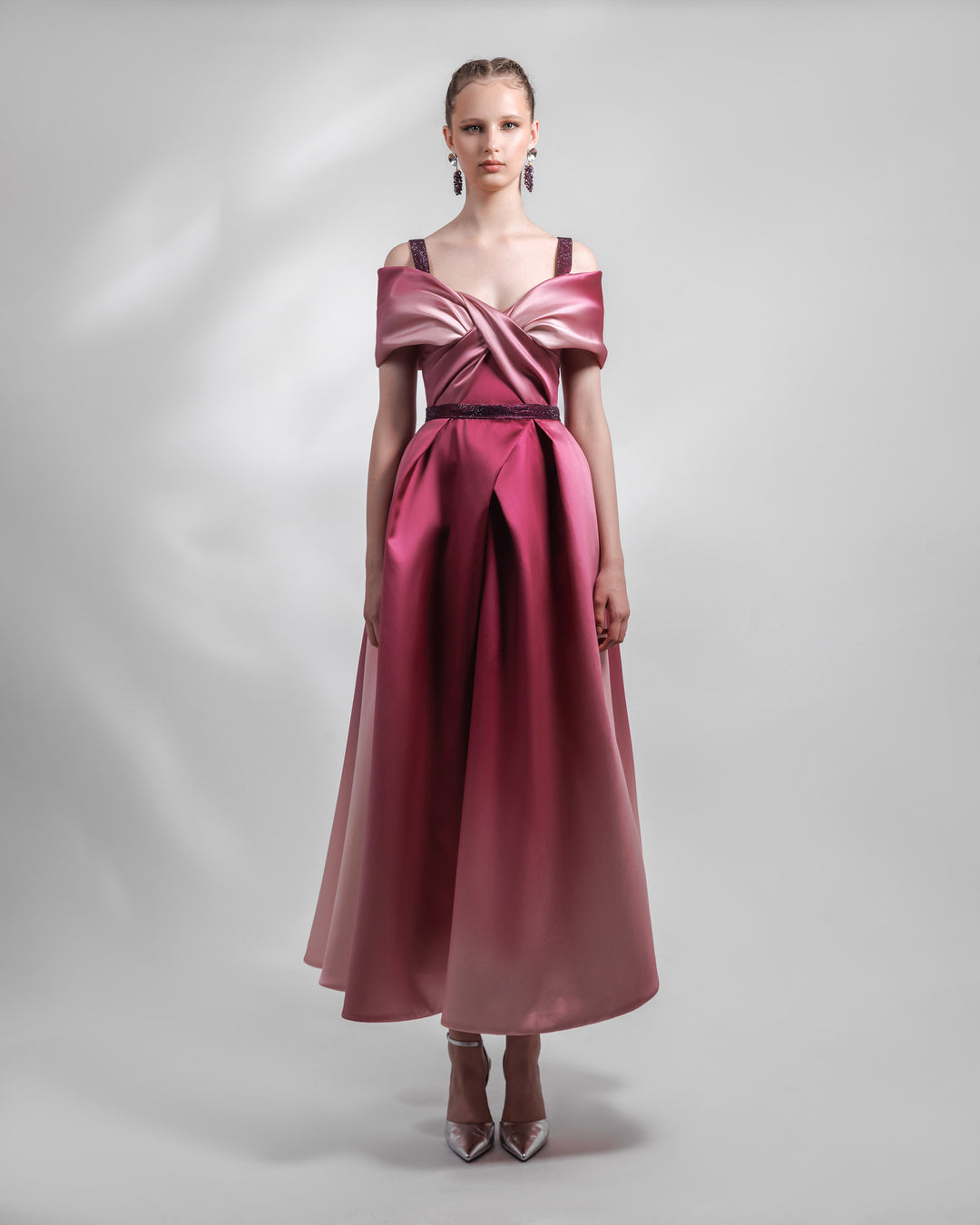 A heavy satin midi dress in pink and burgundy hues, with a bow-like draped bodice, beaded straps and belt, and a pleated skirt.