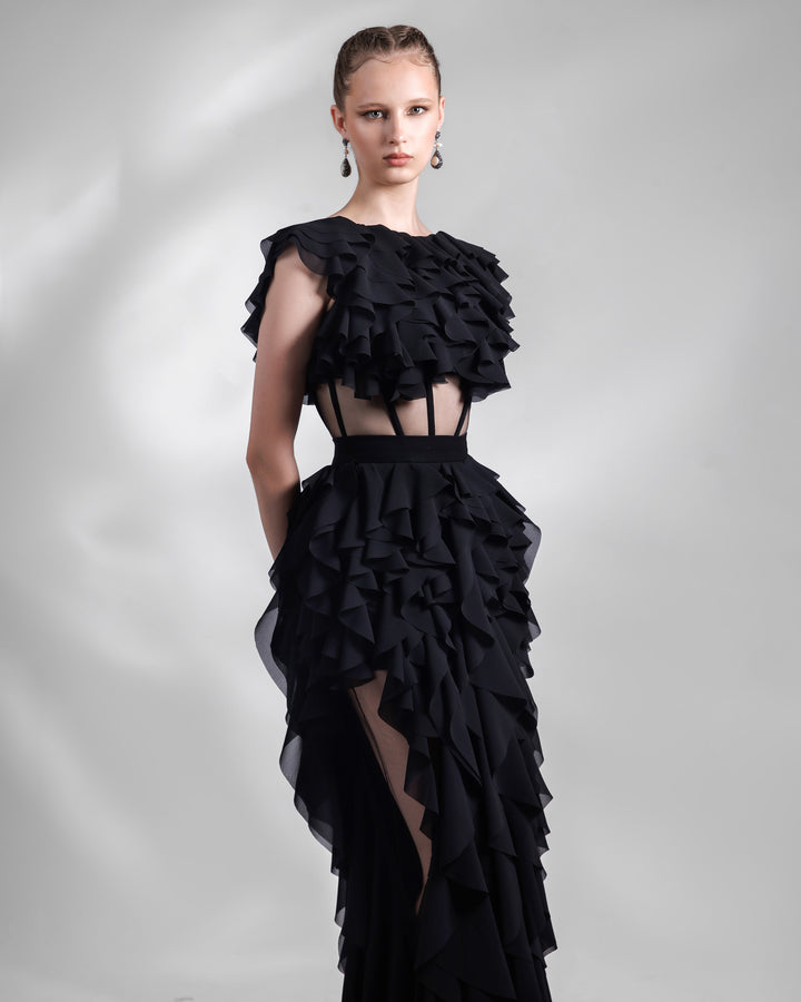 A long fully ruffled chiffon black evening dress featuring a see-through corseted bodice and cutouts on the sides of the skirt.