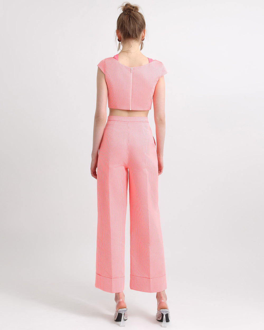 The back of a two tone pink cropped jacquard top with cut out details paired with straight cut cropped jacquard pants.