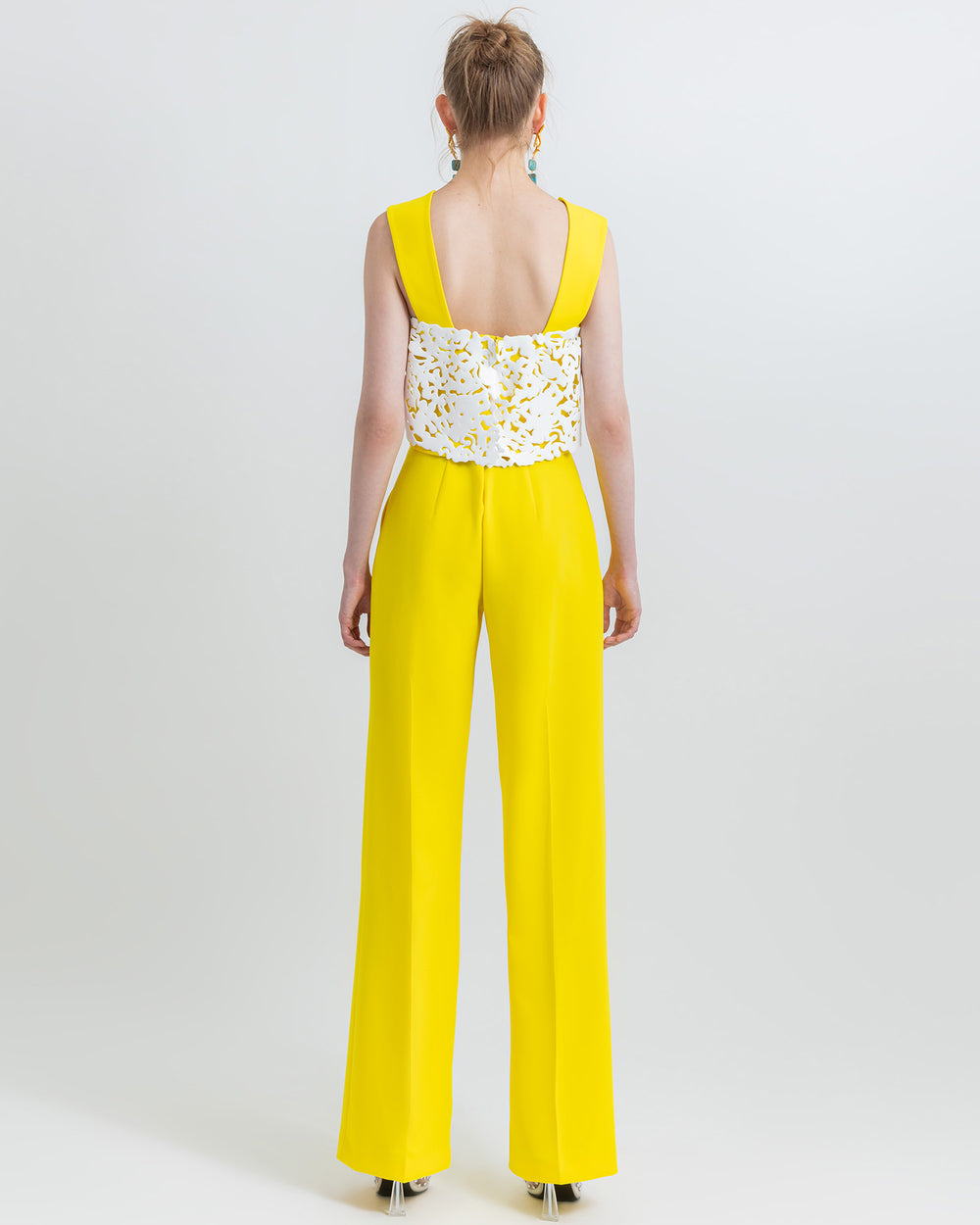 The back of an occasion wear featuring a yellow straight cut crepe pants paired with a cropped crepe top with white laser-cut silicon.