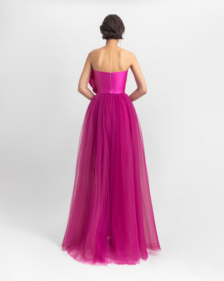 The back of a strapless long fuchsia dress with satin top and fully-pleated tulle from the bottom.