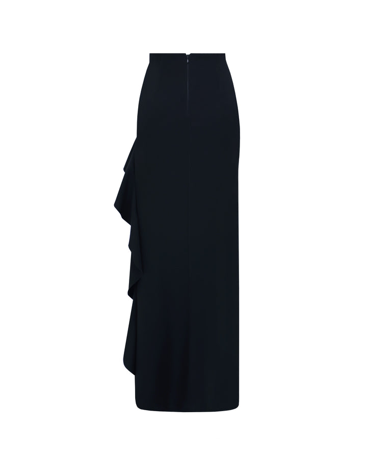 The back of an asymmetrical black crepe skirt with ruffled details and a slit on the side.