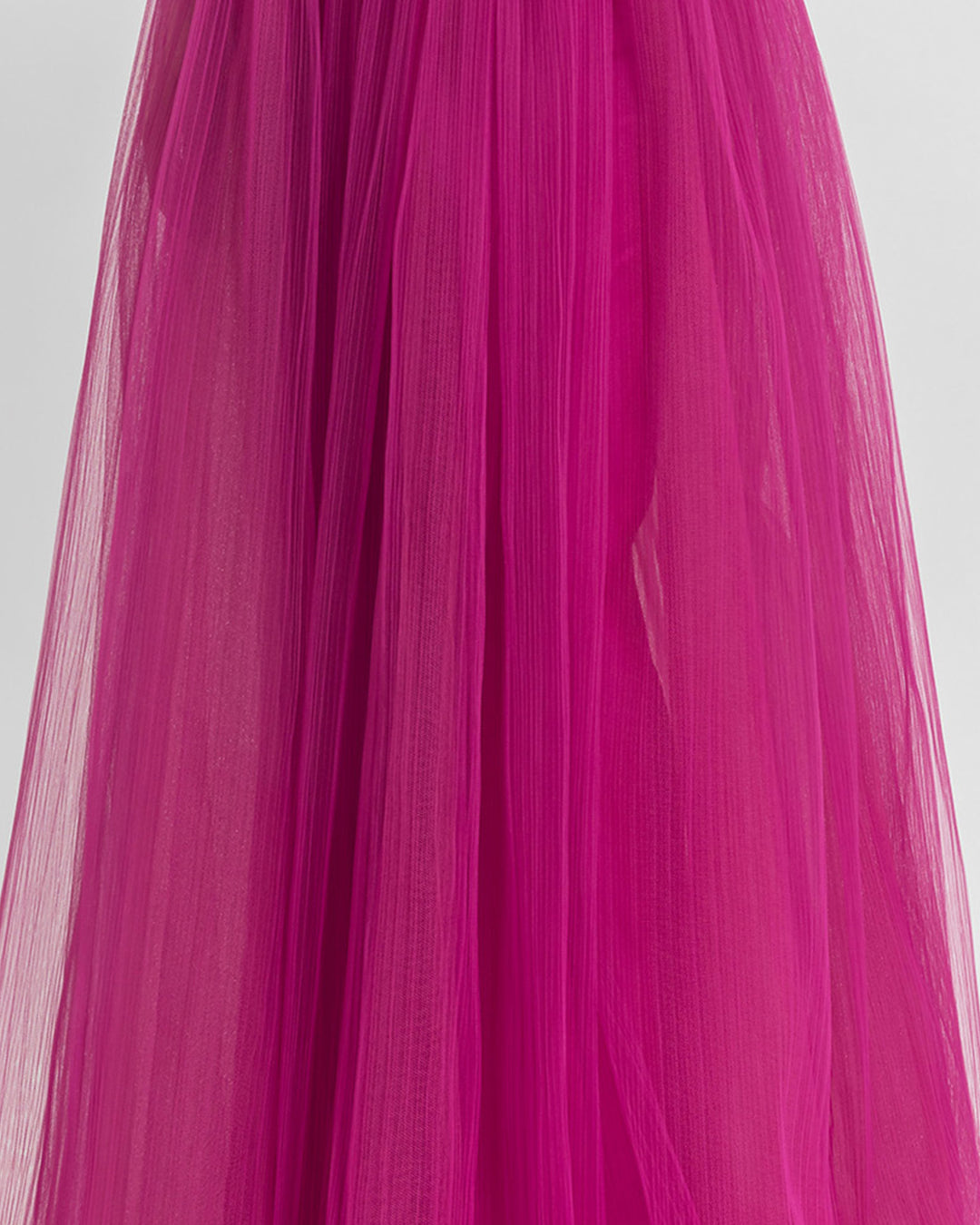 A close-up of a fully-pleated tulle long fuchsia skirt.