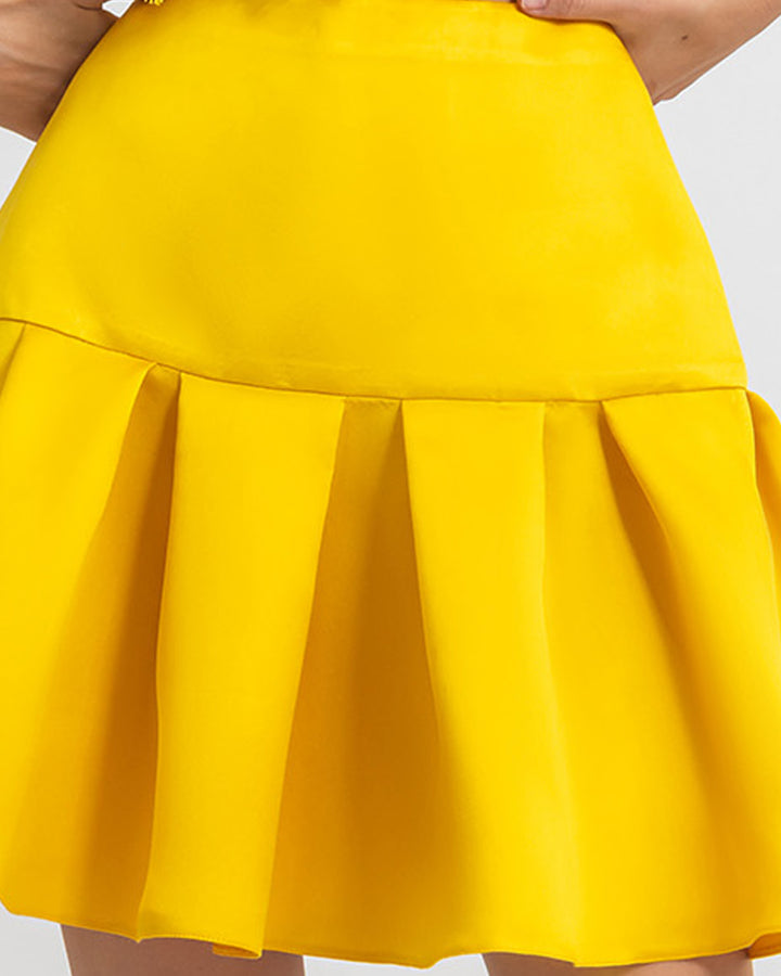 A close up of a heavy satin ruffled mini yellow skirt.