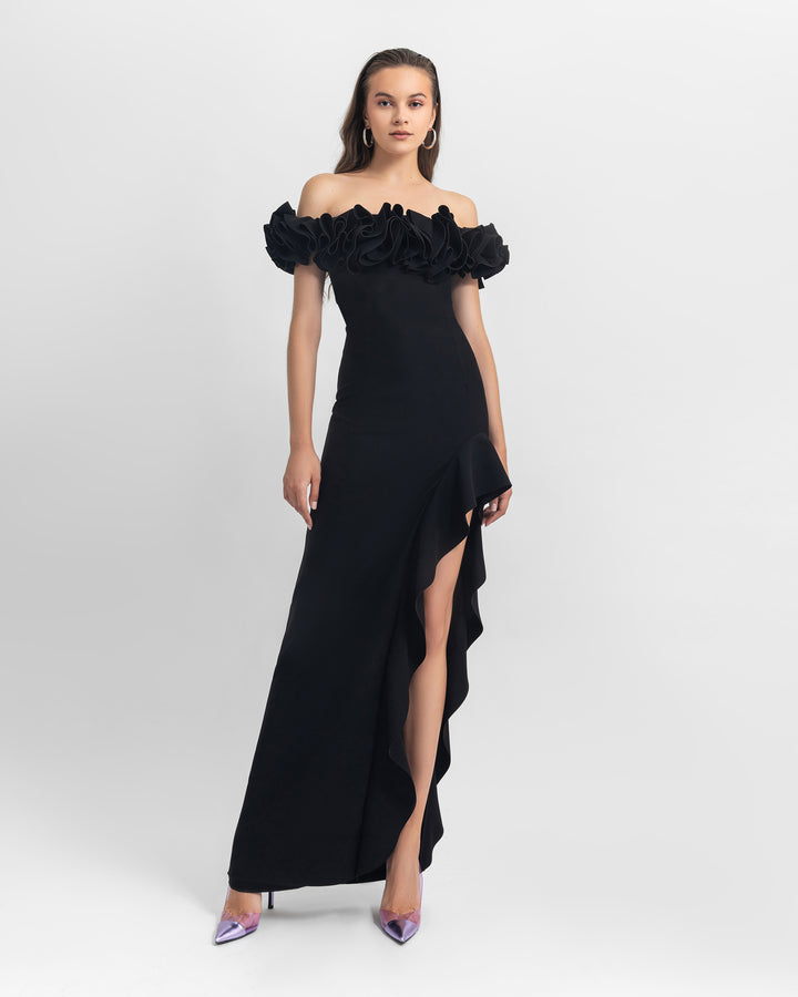 A ruffled off-shoulders crepe black dress with an asymmetrical skirt with ruffled details and a slit on the side.