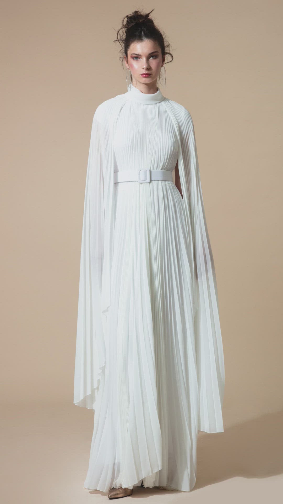 A fully pleated flared chiffon white kaftan dress with cape-like asymmetrical sleeves.