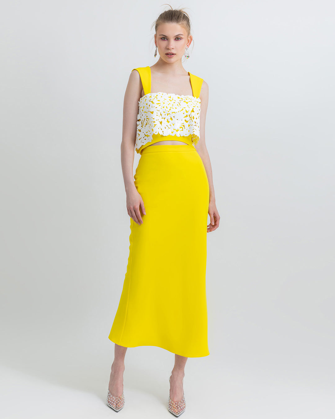 An occasion outfit featuring a yellow cropped crepe top adorned with white laser-cut silicon paired with a midi pencil yellow skirt.